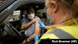 Spencer Jensen, music teacher at the Legacy Preparatory Academy receives the COVID-19 vaccine at the Davis County Legacy Center Tuesday, Jan. 12, 2021, in Farmington, Utah