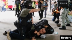 香港警察在逮捕一名參加反對港版國安法遊行示威者的同時舉起手中的胡椒噴劑手槍。（2020年7月1日）