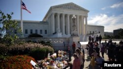  A woman puts flower on a memorial altar as people gather in front of the U.S. Supreme Court following the death of U.S. Supreme Court Justice Ruth Bader Ginsburg, in Washington, U.S., September 19, 2020. REUTERS/Carlos Barria