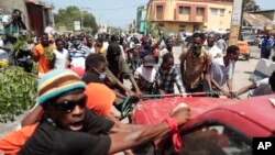 Los manifestantes intentan volcar un automóvil para bloquear una calle durante una protesta contra la inseguridad en Puerto Príncipe, Haití, el lunes 7 de agosto de 2023.