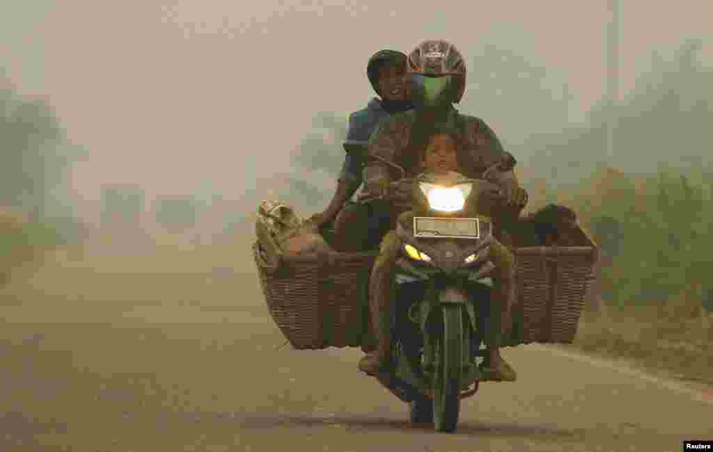 A family rides on a motorcycle as the haze hits Kubu district in Rokan Hilir, Indonesia, June 25, 2013.