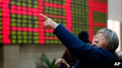 FILE - An investor gestures in front of the stock price monitor at a private securities company in Shanghai, China. 