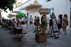 People sit at a bar near Barceloneta beach, after Catalonia's regional authorities and the city council announced restrictions to contain the spread of the coronavirus disease, in Barcelona, Spain, July 19, 2020.