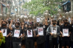 FILE - Anti-coup protesters holding pictures of those who died during a protest against the military offer prayers for them, in Yangon, Myanmar, Monday, April 5, 2021.