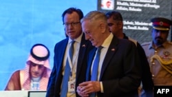 US Defense Secretary James Mattis (C) walks by as Saudi Arabia's Foreign Minister Adel al-Jubeir (L) is seen on a screen addressing the 14th International Institute for Strategic Studies (IISS) Manama Dialogue in the Bahraini capital, Oct. 27, 2018. 