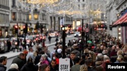 FOTO DE ARCHIVO: Los compradores pasan junto a un mensaje en una estación de desinfectante de manos en medio de la propagación de la pandemia de la enfermedad del coronavirus (COVID-19), en Regent Street, Londres, Gran Bretaña, el 20 de noviembre. REUTERS/Toby Melville/File Photo