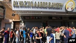 2023 年 10 月 15 日，在以色列對加沙地帶南部汗尤尼斯的襲擊中，流離失所的巴勒斯坦人排隊領取麵包。