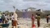 FILE - People walk through rubble after U.S. warplanes killed an Islamist rebel said to be an al-Shabab leader in Somalia, May 1, 2008.