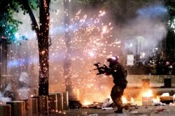 A federal officer fires crowd control munitions at Black Lives Matter protesters at the Mark O. Hatfield United States Courthouse, July 24, 2020, in Portland, Oregon.
