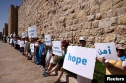 Warga menyerukan diakhirinya kekerasan di tengah pertempuran Israel-Gaza, di sepanjang bagian tembok Kota Tua Yerusalem, 19 Mei 2021. (Foto: REUTERS/Ronen Zvulun)