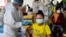 FILE - Health officials in personal protective equipment (PPE) inoculate people with the second dose of China's Sinopharm Covid-19 coronavirus vaccine at a pagoda in Phnom Penh on May 20, 2021, as part of the government's campaign to halt the rising number of cases. (AFP)