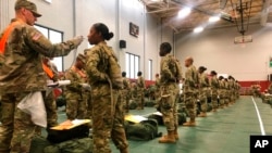 FILE - In this image provided by the U.S. Army, recent Army basic combat training graduates have their temperatures taken as they arrive at Fort Lee, Va., on March 31, 2020, after being transported using sterilized buses from Fort Jackson, S.C. COVID-19 h