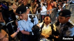 Student protest leader Joshua Wong shouts as he is carried by policemen.