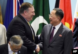 U.S. Secretary of State Mike Pompeo, left, greets North Korea's Foreign Minister Ri Yong Ho as they prepare for a group photo at the 25th ASEAN Regional Forum Retreat in Singapore, Aug. 4, 2018.