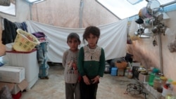 FILE - Syrian siblings, displaced from eastern Idlib province, pose for a picture in a tent at Atmeh camp in Syria, near the Turkish border, June 19, 2020.