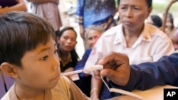 A U.S sailor gives a medical treatment to a Cambodian boy at a Buddhist pagoda, outside of Sihanoukville city, file photo. 