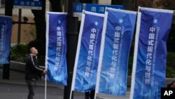 一名工人在上海街頭整理豎立的宣傳旗幟：“中國式現代化與世界”。 （2023年4月21日）