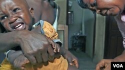 Aliyatu Abdulai (kanan), petugas Klinik Kesehatan Ibu dan Anak di Sierra Leone, sedang memvaksinasi sorang anak di desa Sembehun. Sierra Leone adalah salah satu negara yang mendapat program bantuan pendanaan vaksin dari GAVI.