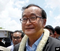 FILE - In this Aug. 16, 2015, file photo, Sam Rainsy, leader of the opposition Cambodia National Rescue Party, greets his party supporters upon his arrival at Phnom Penh International Airport in Phnom Penh, Cambodia.