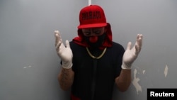 Flavio Falcone, a psychiatrist, wears gloves and a protective face mask in the elevator of the building where he lives as he makes his way to perform as a clown in an area known as "cracolandia," or crackland in Sao Paolo, Brazil. REUTERS/Amanda Perobelli