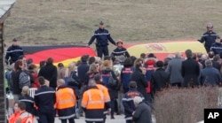 French gendarmes hold German and Spanish flags as family members of people involved in the Germanwings jetliner that crashed in the French Alps attend a gathering in Le Vernet, March 26, 2015.