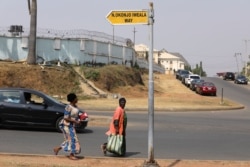 Two women ran across a street named after Ngozi Okonjo-Iweala, in Wuye district in Abuja, Nigeria, Feb. 15, 2021.