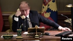 FILE - Russian President Vladimir Putin sits at a table during a telephone conversation in St. Petersburg, Russia, Dec. 15, 2018.