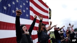 Members of the Proud Boys cheer on stage as they and other right-wing demonstrators rally, Saturday, Sept. 26, 2020, in Portland, Ore. (AP Photo/John Locher)