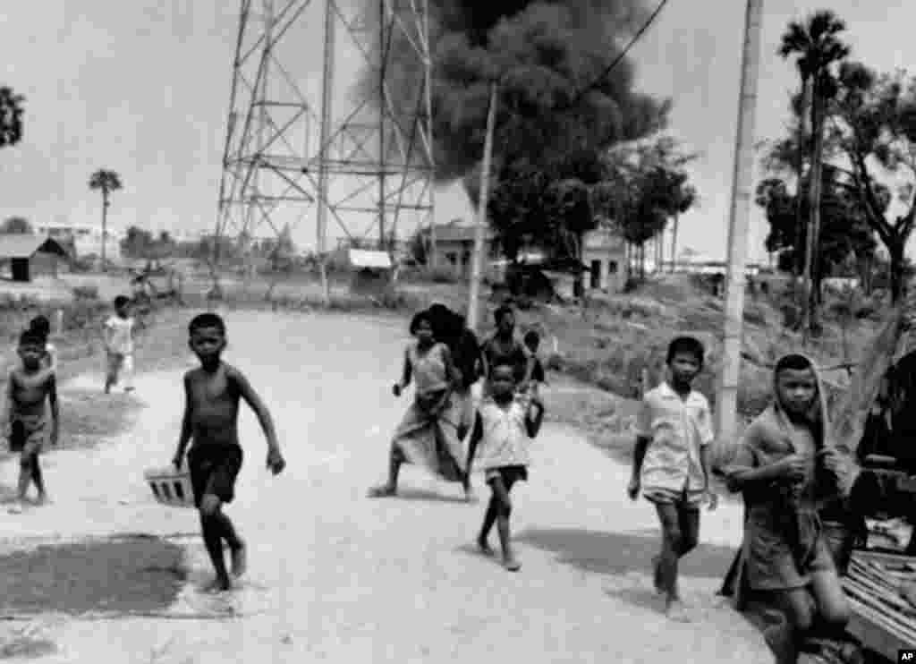 ក្មេងៗ​រត់​គេច​​ពី​អគារ​ដែល​ឆេះ​​ដោយ​ត្រូវ​គ្រាប់​ផ្លោង​នៅ​ជិត​អាកាសយានដ្ឋាន​ភ្នំពេញ​ ក្នុង​ថ្ងៃ​ដែល​ទីក្រុង​នេះ​បាន​ធ្លាក់​ក្នុង​កណ្តាប់ដៃ​ទ័ព​ខ្មែរក្រហម​កាល​ពី​ថ្ងៃ​ទី​១៧ ខែ​មេសា ឆ្នាំ​១៩៧៥។ (AP Photo)