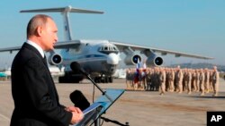 FILE - In this Dec. 12, 2017 file photo, Russian President Vladimir Putin addresses the troops at the Hemeimeem air base in Syria.