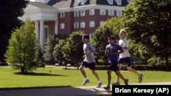 Joggers run through the campus of Wheaton College in Wheaton, Ill.