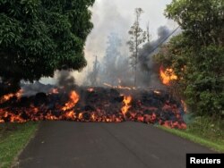 FILE - A lava flow from the Kilauea volcano moves on a street in Leilani Estates in Hawaii, May 6, 2018.