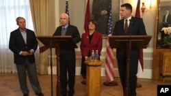 Latvian President Raimonds Vejonis (right) looks at US Sen. John McCain, (center left) during a press conference, Dec. 28, 2016, in Riga, Latvia, while Lindsey Graham, R-SC., and Amy Klobuchar, D-Minn., stand in the background. 