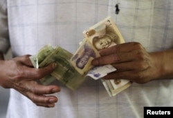 FILE - A customer counts Chinese Yuan notes at a market in Beijing, Aug. 12, 2015.