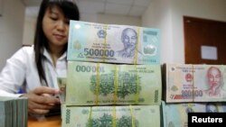 An employee counts Vietnamese dong banknotes at a counter of the Vietnam International Bank in Hanoi November 3, 2011. REUTERS/Kham (VIETNAM - Tags: BUSINESS)