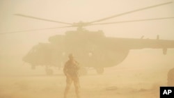 FILE - Russian soldier stands guards as military helicopter takes off at an airport in Deir el-Zour, Syria, Sept. 15, 2017.