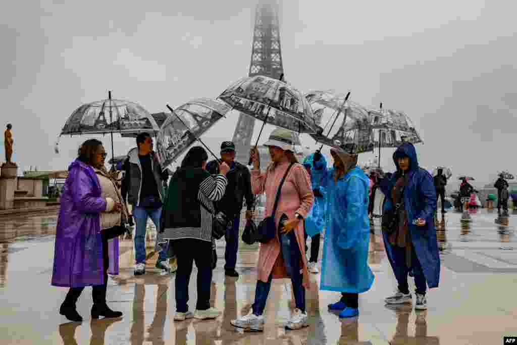Visitors shelter from the rain with umbrellas on the Parvis des Droits de l'Homme on Esplanade du Tocadero across from the Eiffel Tower, as remnants of hurricane Kirk cause heavy rainfall over Paris, France.