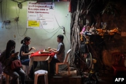 FILE - A fortune-teller, right, attends to a customer in Bangkok, Feb. 12, 2019.