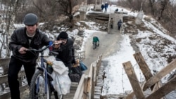 Local residents walk across a bridge damaged during fighting between Ukrainian government forces and Russia-backed rebels in Stanytsia Luhanska, Luhansk region, eastern Ukraine, Jan. 16, 2016.