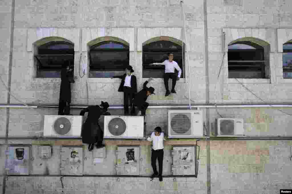 Ultra-Orthodox Jewish boys climb down a wall near the scene of a suspected attack, in Jerusalem, Aug. 4, 2014.
