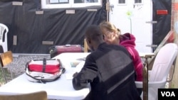 A migrant is seen studying at Zimako Jones' school, one of several makeshift schools at the Jungle camp in Calais, France. (L. Bryant/VOA)