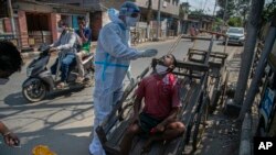 A health worker takes a nasal swab sample of a cartpuller during random testing for COVID-19 in a market in Gauhati, India.