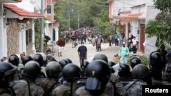 Guatemalan soldiers block a street as Honduran migrants gather after Guatemalan security forces cleared a road where they were camping after authorities halted their trek to the United States, in Vado Hondo, Guatemala, Jan. 18, 2021. 