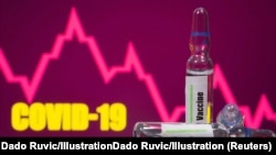 A test tube labelled with the Vaccine is seen in front of Covid-19 and stock graph logo in this illustration taken