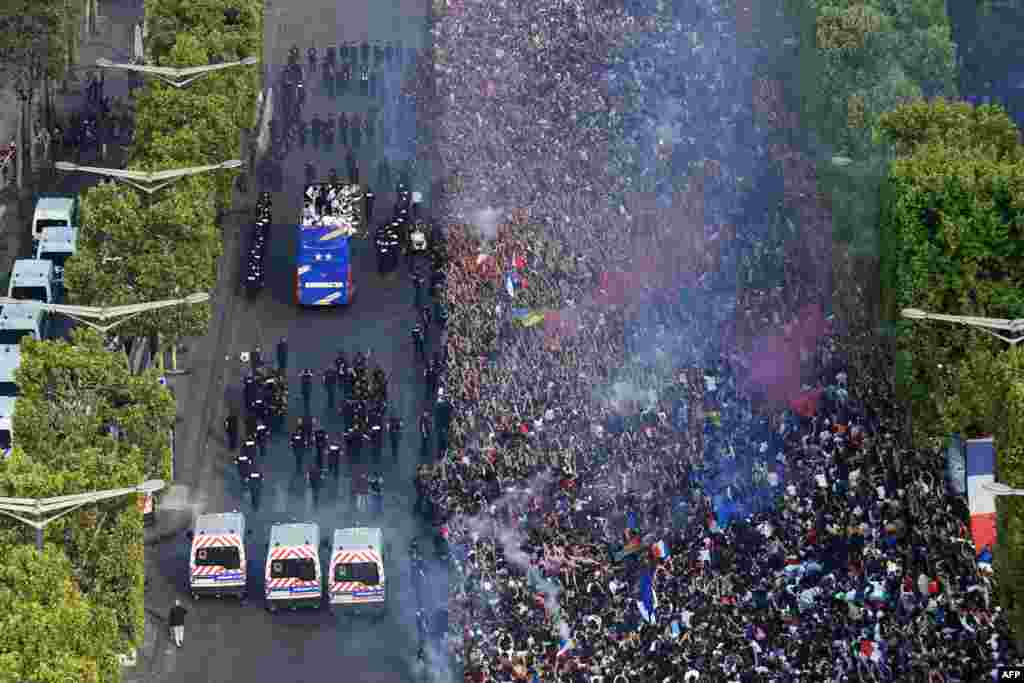 Fans greet France's national football team players as they celebrate on the roof of a bus while they parade down the Champs-Elysee avenue in Paris, after winning the Russia 2018 World Cup final football match.
