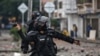 Un oficial de policía se prepara para lanzar una granada aturdidora a los manifestantes durante un paro nacional contra la reforma tributaria en Cali, Colombia, el lunes 3 de mayo de 2021.