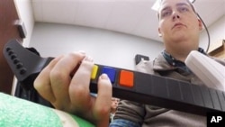In this March 2016 photo provided by Ohio State University, Ian Burkhart plays a guitar video game as part of a study with neural bypass technology at The Ohio State University Wexner Medical Center in Columbus. A computer chip in Burkhart's brain reads h