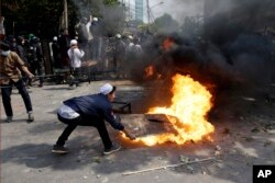 Protesters try to put out fire from a burning tyre in Jakarta, Indonesia, Wednesday, May 22, 2019.