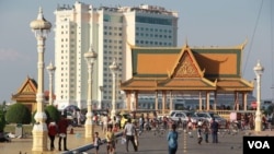 មនុស្សម្នាដើរកម្សាន្តមុខព្រះបរមរាជវាំង ក្រុងភ្នំពេញ កាលពីខែឧសភា ឆ្នាំ២០១៥ ដែលនៅម្ខាងទៀតនៅទន្លេសាប មានអគារសណ្ឋាគារសុខាដែលទើបសាងសង់រួចលូតផុតឡើង។ (អូន ឆេងប៉រ/VOA)