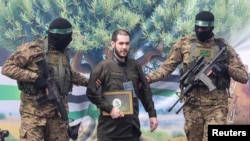 Eliya Cohen, mateka wa Israel aliyekuwa anashikiliwa na Hamas akishindikizwa na wanamgambo wa Hamas, huko Nuseirat, katika Ukanda wa Gaza, Februari 22, 2025. Picha ya Reuters